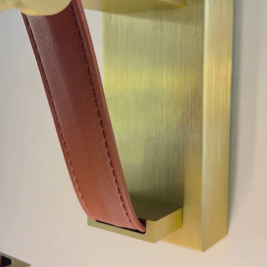 Dual vertical LED leather wall sconce with brushed brass base for luxury lighting decor.