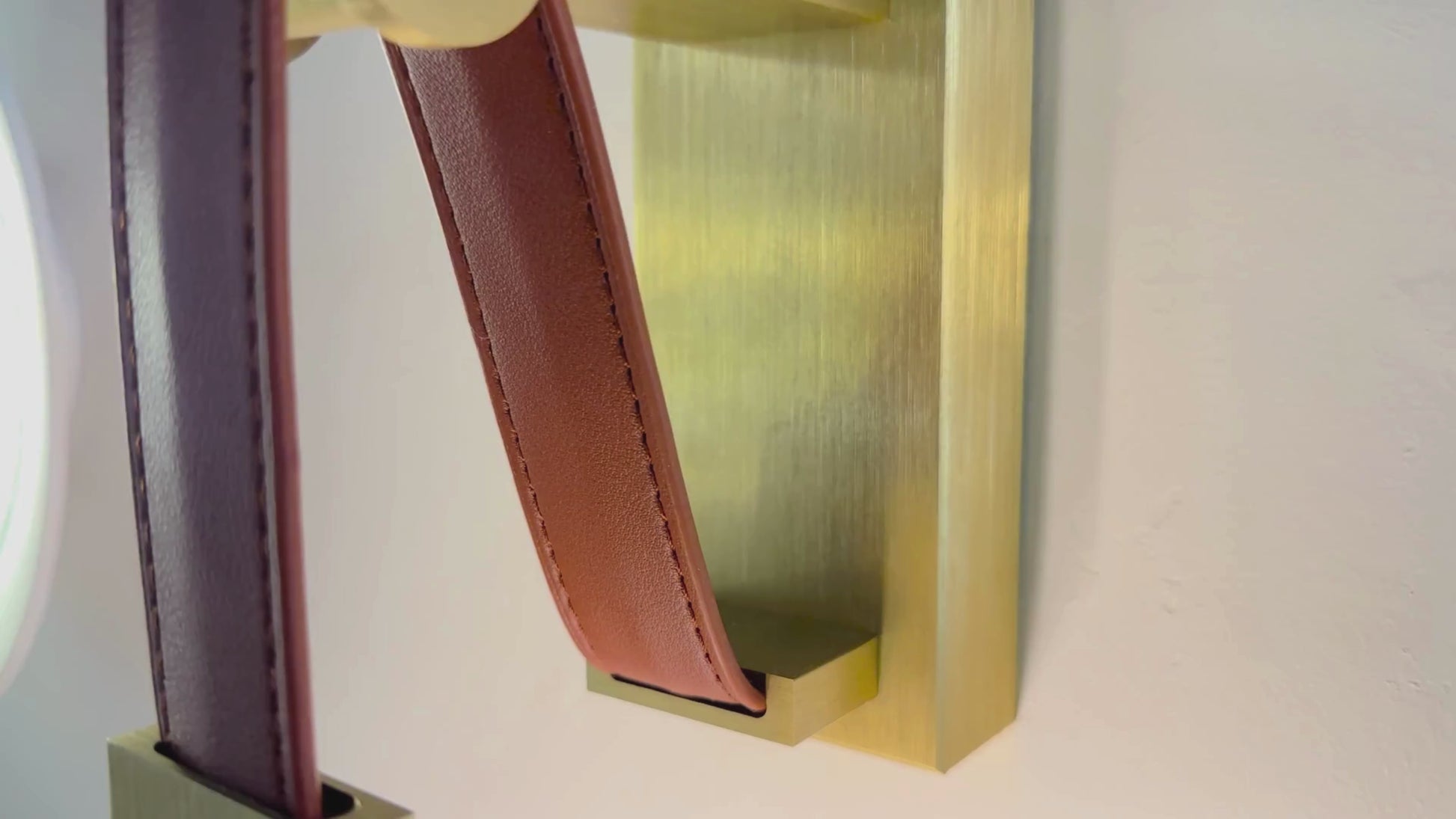 Dual vertical LED leather wall sconce with brushed brass base for luxury lighting decor.