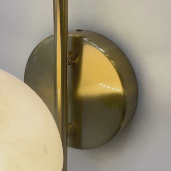 Modern marble sconce with brass backplate and warm glowing dome.
