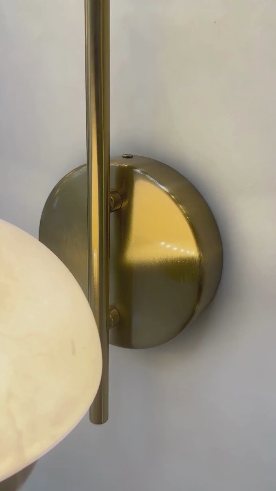 Modern marble sconce with brass backplate and warm glowing dome.