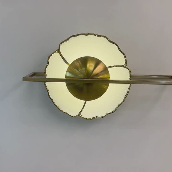 Fluted porcelain wall sconce with brass frame and warm halo lighting mounted on a paneled wall.