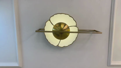 Fluted porcelain wall sconce with brass frame and warm halo lighting mounted on a paneled wall.