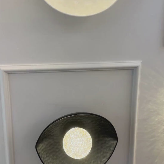 A symmetrical setup of black and white plexiglass LED sconces mounted on a paneled wall emits soft ambient light.