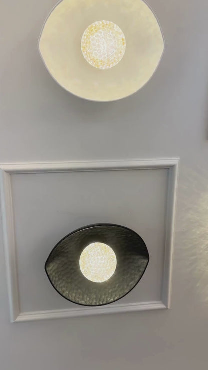 A symmetrical setup of black and white plexiglass LED sconces mounted on a paneled wall emits soft ambient light.