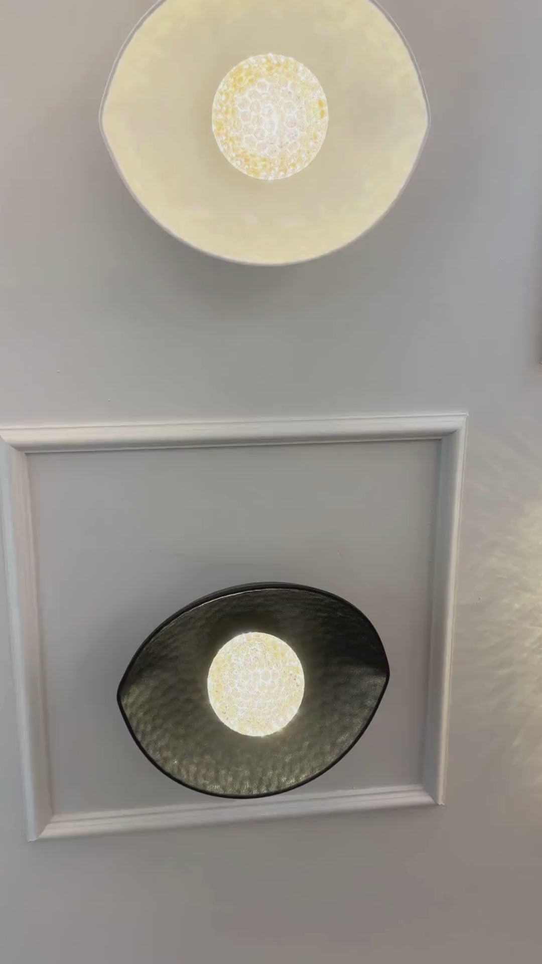 A symmetrical setup of black and white plexiglass LED sconces mounted on a paneled wall emits soft ambient light.