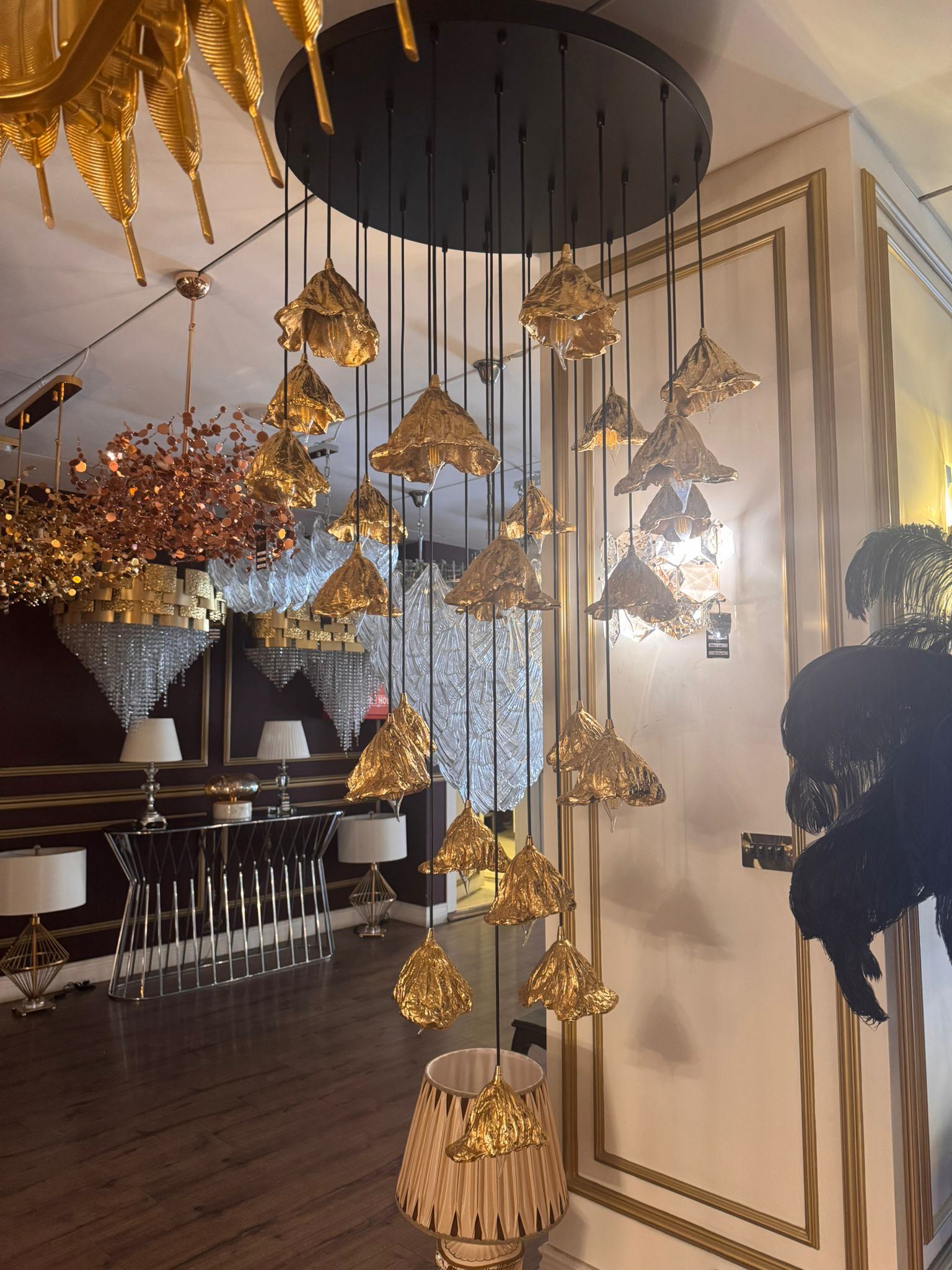 Sculptural pure brass leaf pendant lights suspended in a luxury lighting showroom.