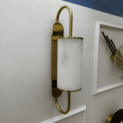Side view of a contemporary brass and alabaster wall light fixture on a white wall.
