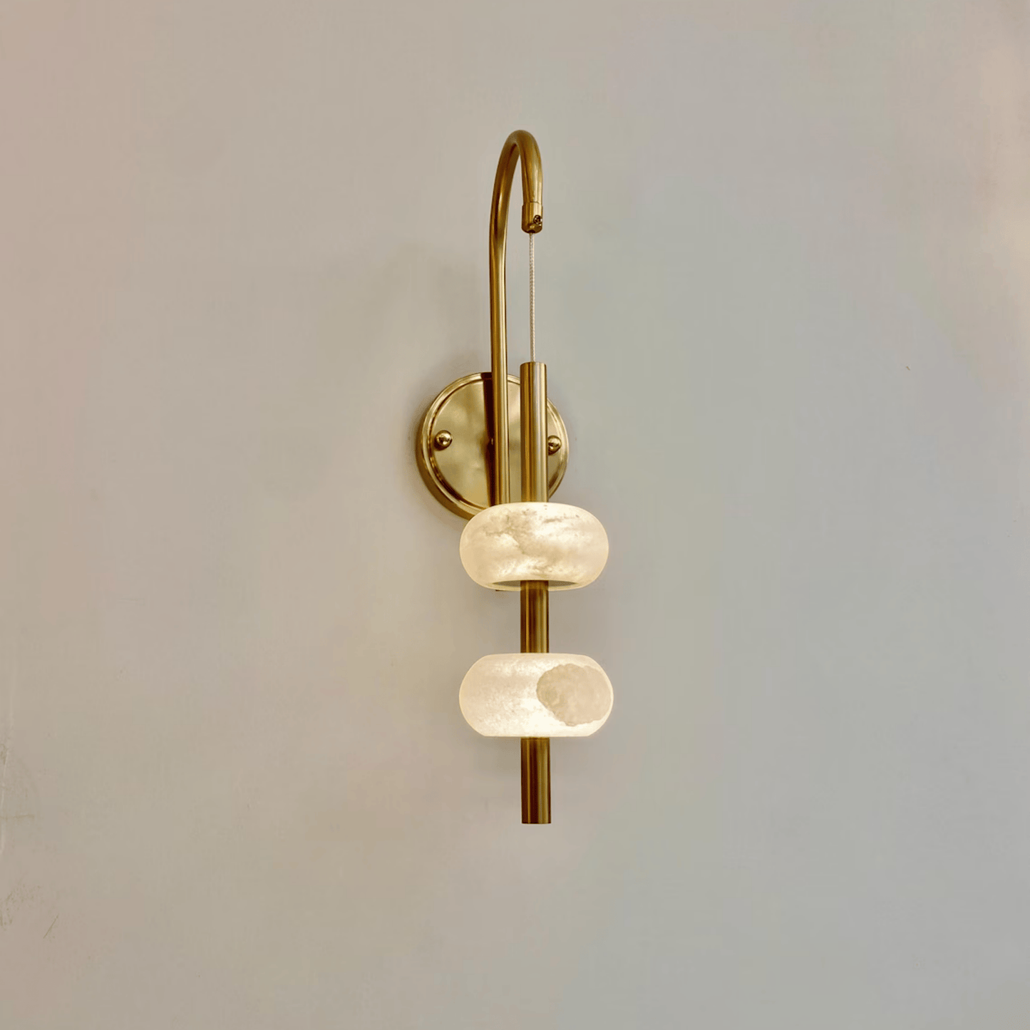 Slim modern alabaster wall light with brass hardware and warm lighting glow.