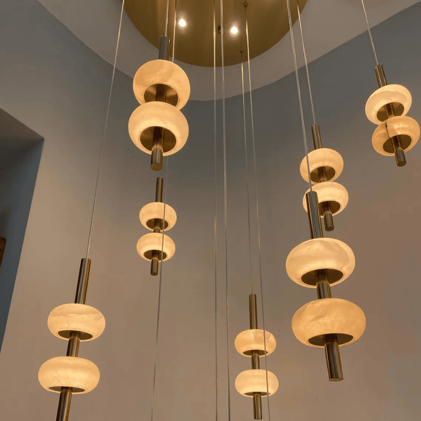 Sculptural installation of alabaster pendant lights suspended from ceiling plate in modern interior.