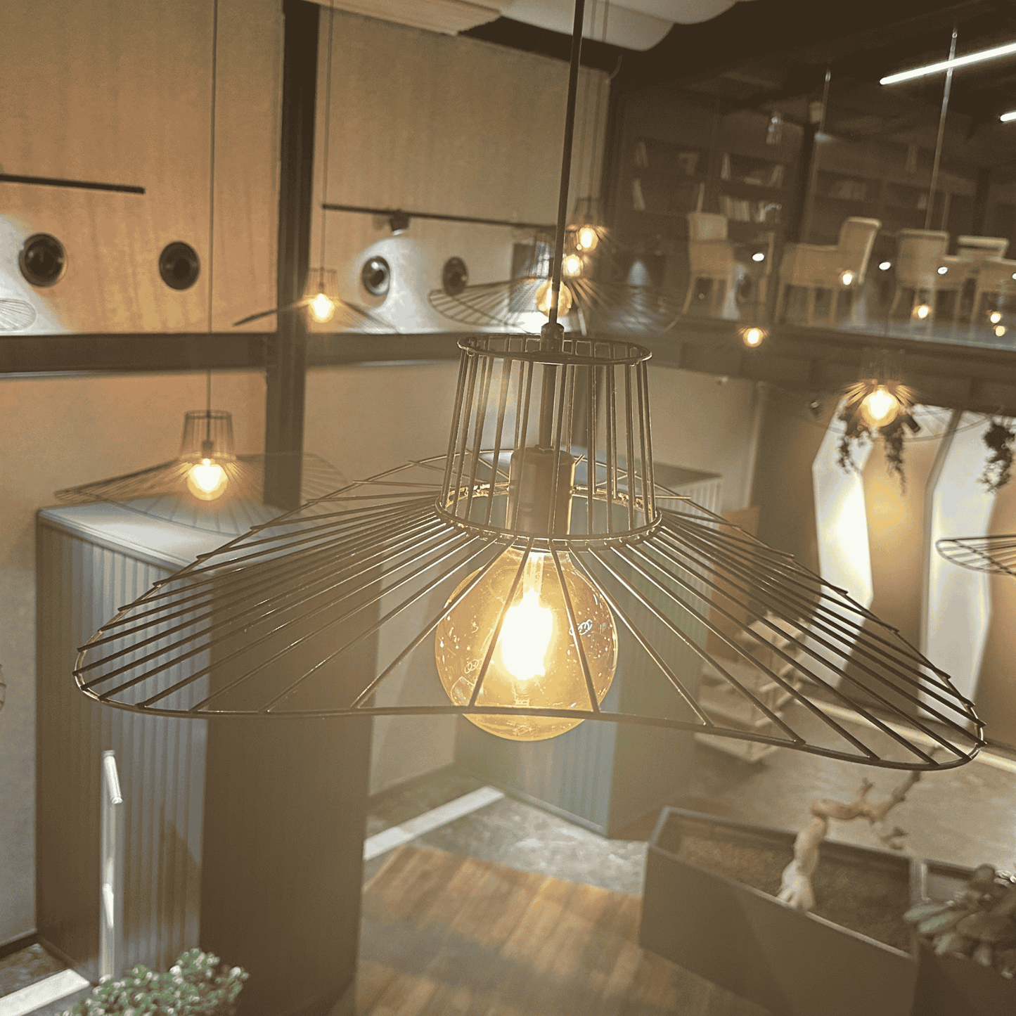 Close-up view of sculptural straw hat pendant light with a glowing bulb in modern ceiling setup.