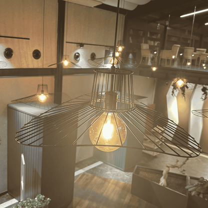 Close-up view of sculptural straw hat pendant light with a glowing bulb in modern ceiling setup.