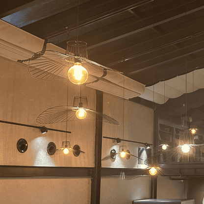 Double straw hat pendant lights with wireframe design and glowing filament bulbs in a stylish interior.
