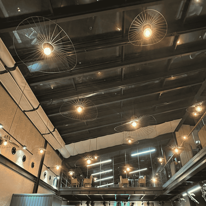 Cluster of straw hat pendant lights suspended from a vaulted ceiling in an industrial-style interior.