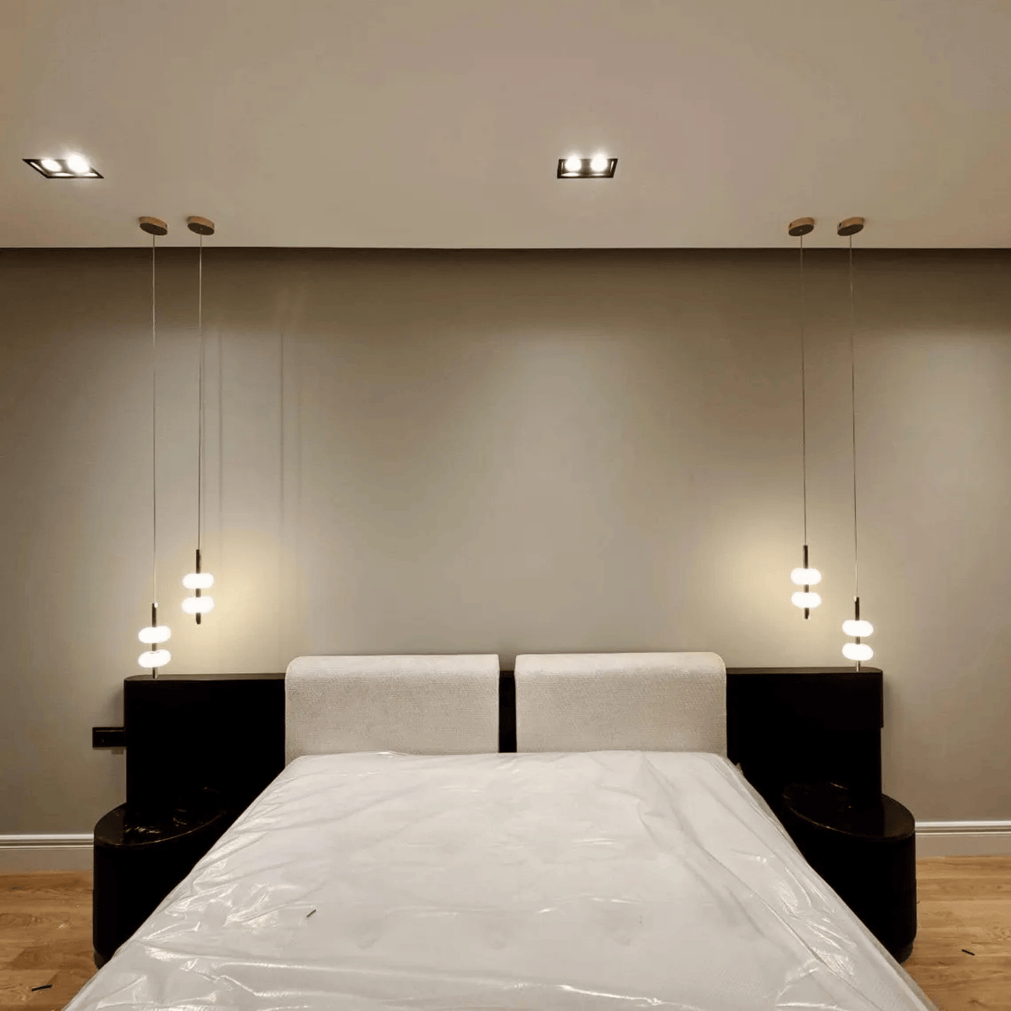 Symmetrical alabaster pendant lights hanging beside bed in minimalist bedroom interior.