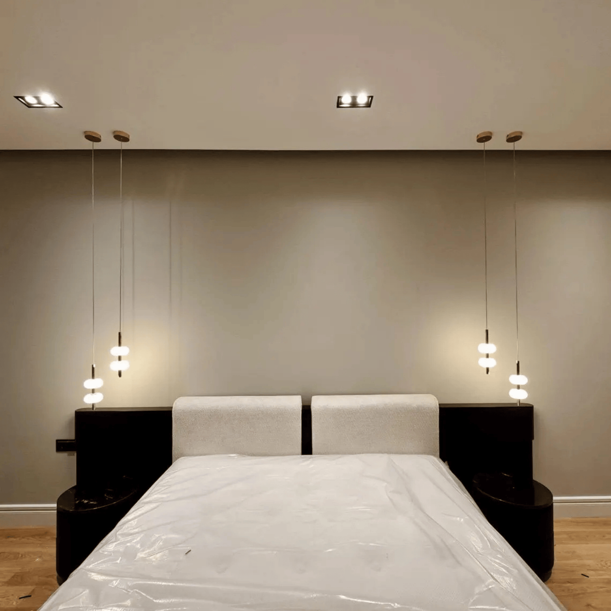Symmetrical alabaster pendant lights hanging beside bed in minimalist bedroom interior.