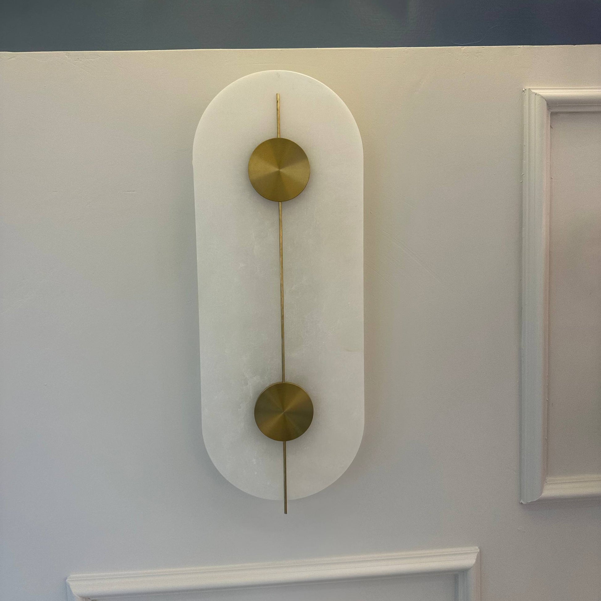 Unlit alabaster wall sconce with visible natural stone and brass detailing.