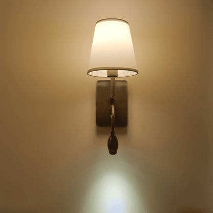 Wall sconce with metallic finish and flexible light casting a downward glow.