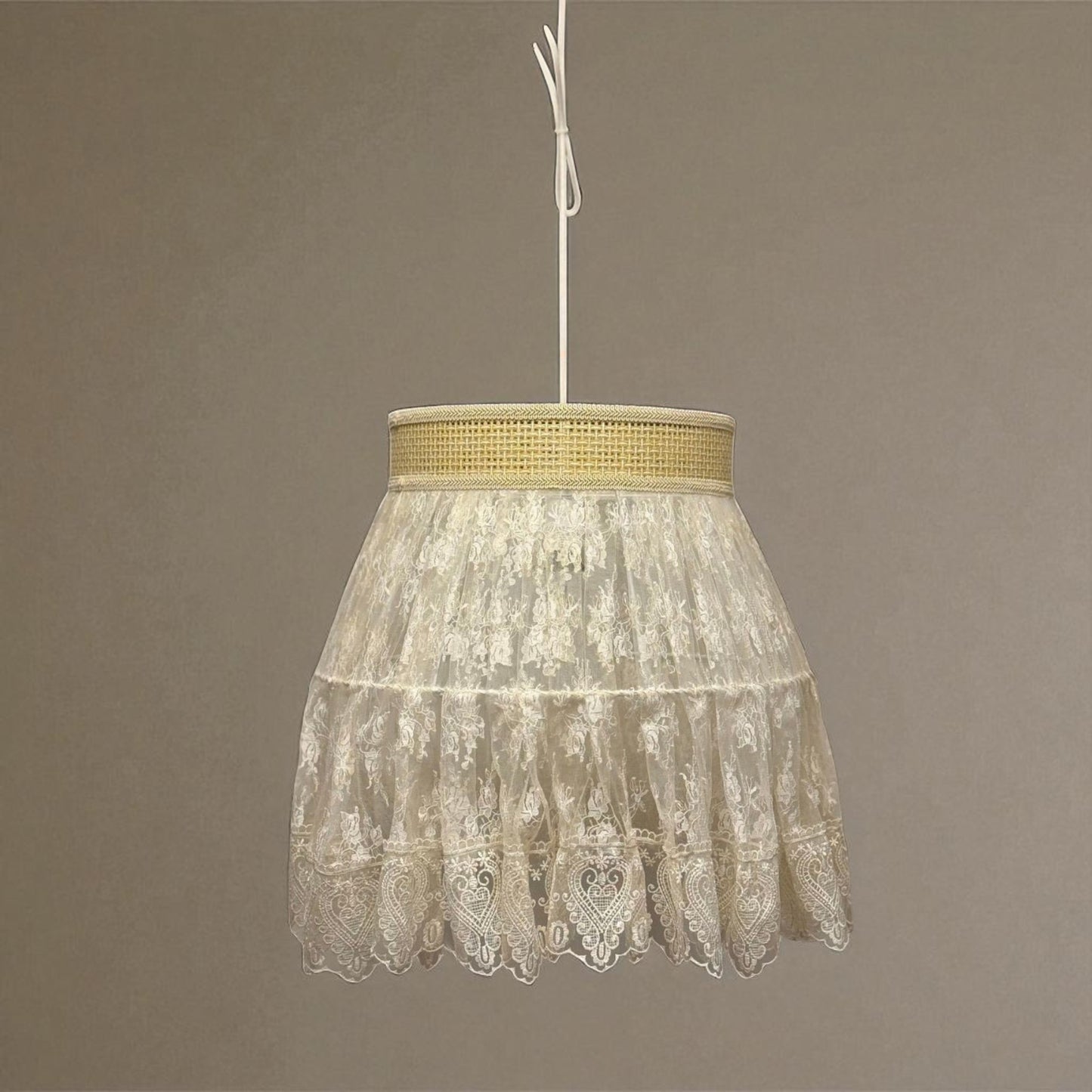Vintage lace pendant light glowing softly in a formal room with traditional mirror and floral arrangement.