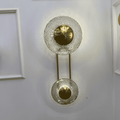 Brass-finish living room wall sconce with textured glass discs, vertical design.