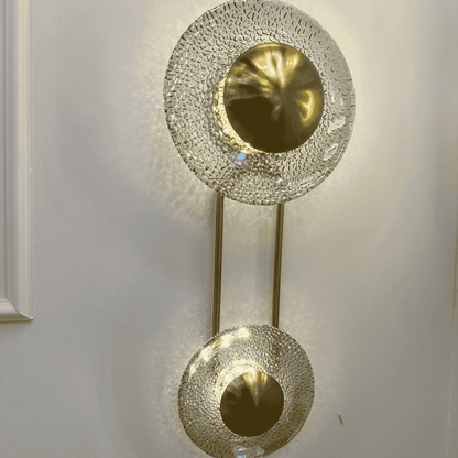 Close view of brass dome and patterned glass discs on living room wall sconce.